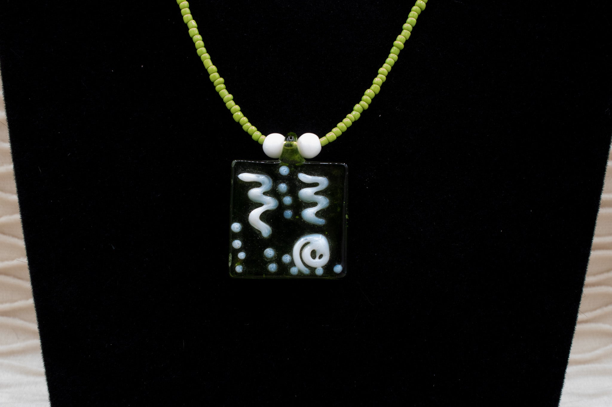 A Green Glass Pendent Adorned on a Dainty Green Beaded Necklace